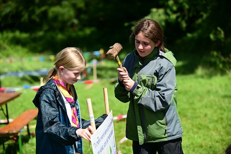 2 Guides settign up a sign for their camp using a hammer
